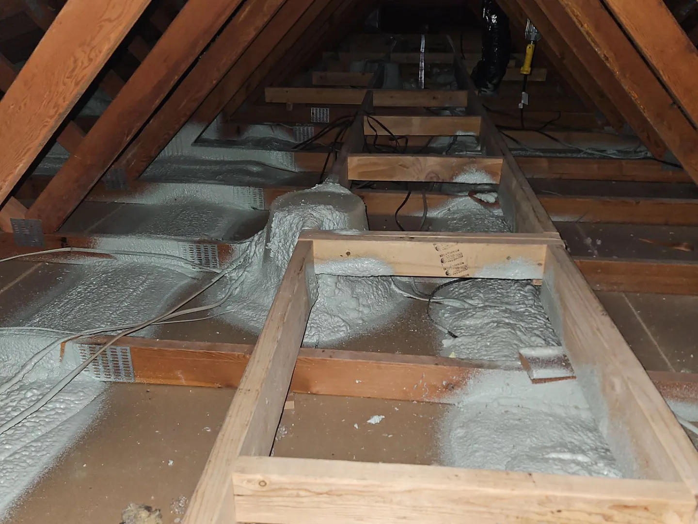 PowerHouse technician air sealing attic penetrations in a Longmont home before adding insulation
