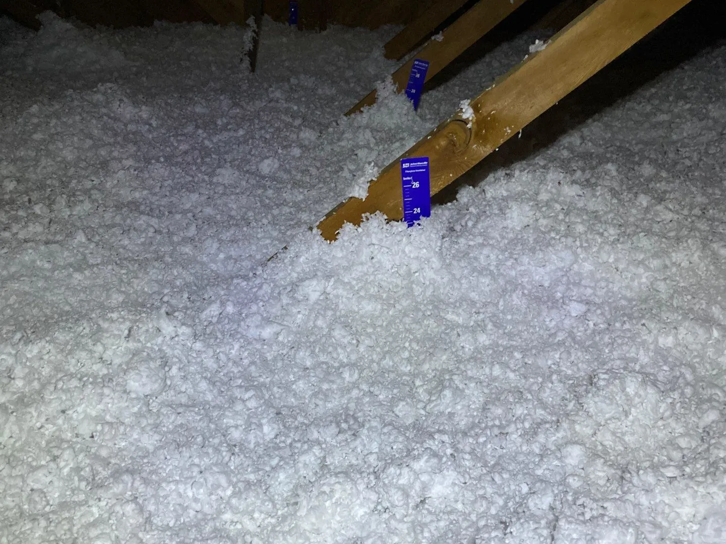 Blown-in attic insulation on a PowerHouse job in Longmont, with the depth marker showing the finished depth