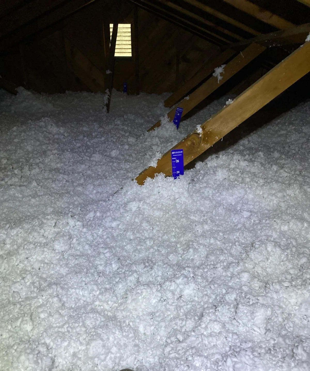 Blown-in attic insulation in a Longmont home with a depth marker showing the finished insulation depth