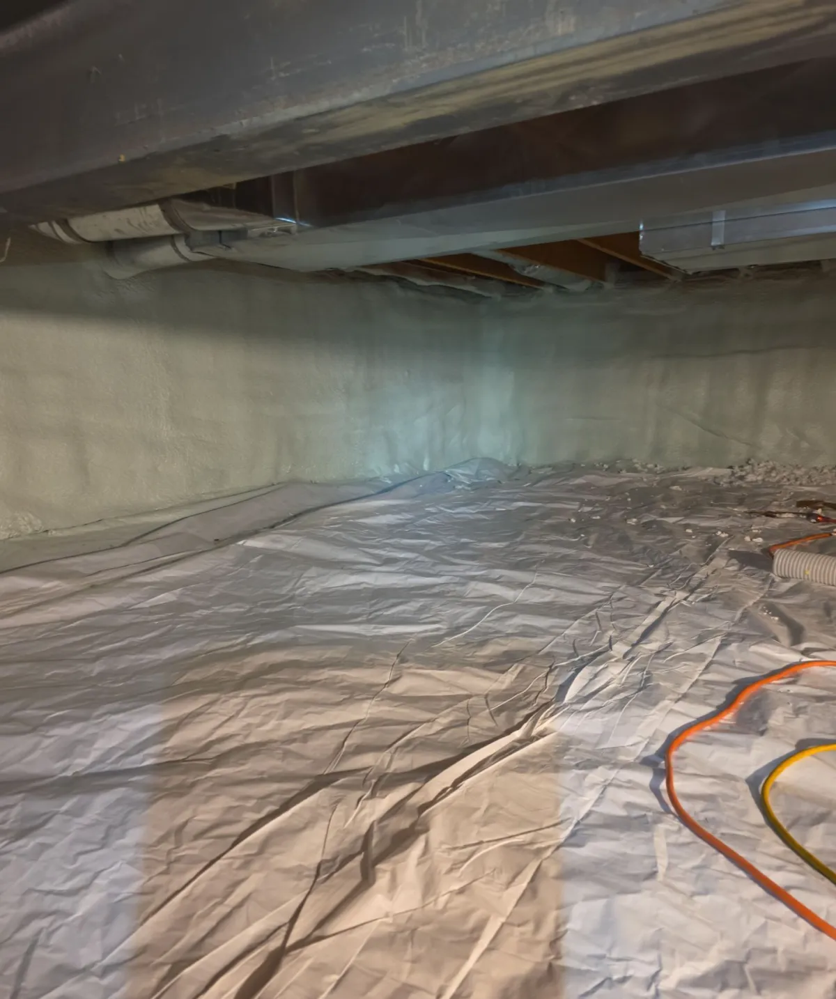 Encapsulated crawl space with a sealed vapor barrier across the floor and closed-cell spray foam on the foundation walls