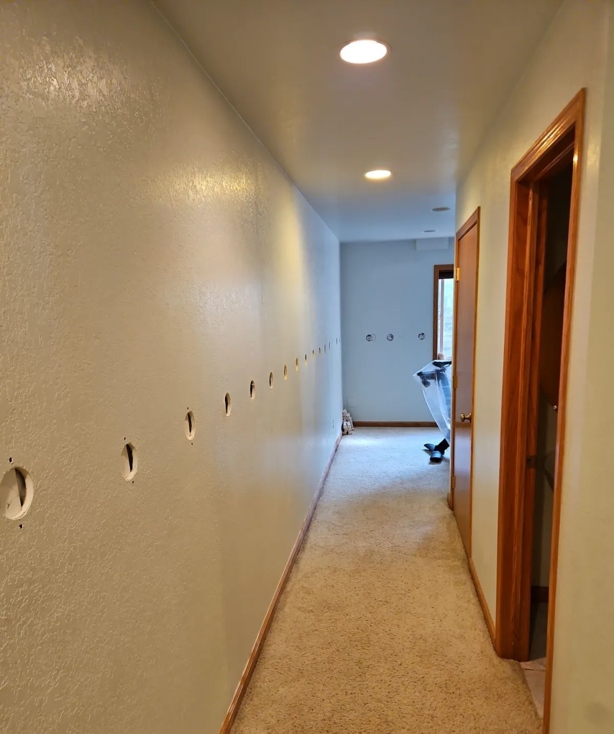 Interior wall in a Fort Collins home with a row of drill holes for dense-pack insulation, ready to be patched