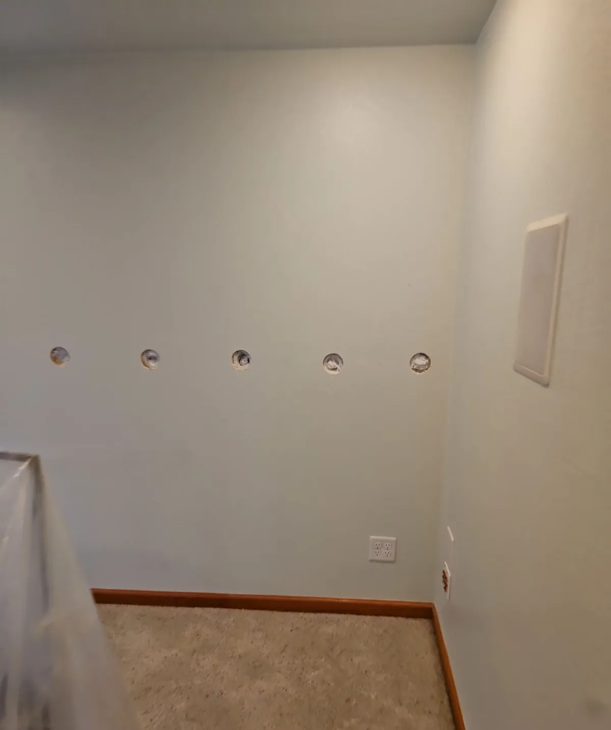 Hallway wall in a Fort Collins home showing the small access holes used to dense-pack the exterior wall cavities
